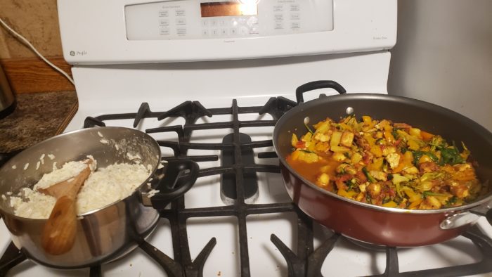 Pan with tofu, veggies and sauce served alongside pot of rice.